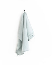 MagicLinen - Ruffle trim tea towel hanging on a hook, showcasing its soft, durable linen texture and practical hanging loop, perfect for any kitchen task.