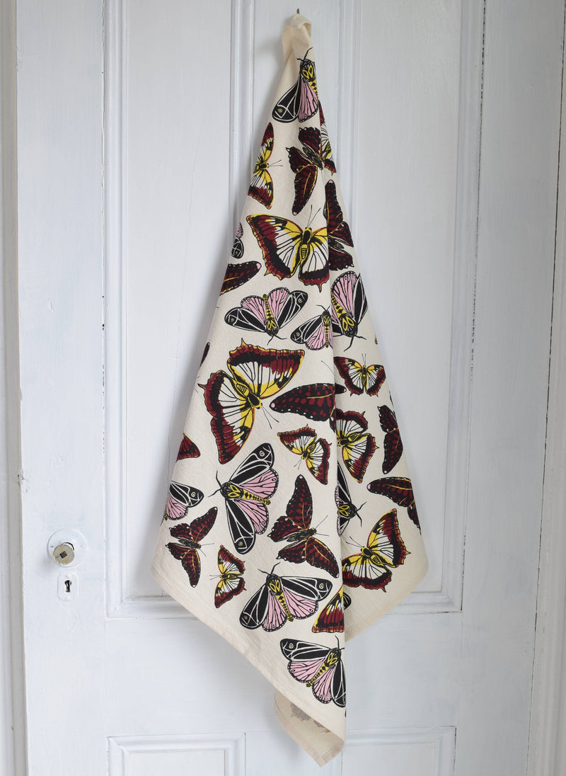 Hearth and Harrow - Butterfly Tea Towel, oversized 30x30, hangs on a door, showcasing eco-friendly, hand-printed butterfly designs on organic cotton.
