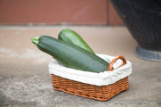 Two fresh green zucchinis in a wicker basket, featuring Bentley Seed Co.'s Zucchini-Black Beauty Squash 1957, ideal for prolific home gardening and versatile cooking.