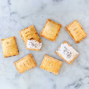 FarmSteady - Pastry Tart Making Kit: Seven golden-brown, crimped hand-pies on marble, two with white icing and lavender, showcasing artisanal, nostalgic baking from Athens Cooks.