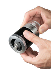 Peugeot Maestro Pepper Bar grinder with adjustable grind size, held by two hands, part of a gift set with jars and premium peppers.