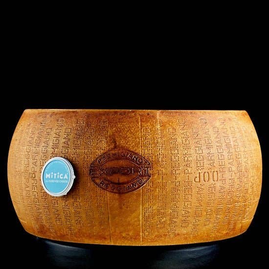 Nicola's Marketplace - Parmigiano Reggiano DOP Mitica® 36 months: 7 Ounces, full wheel with dotted rind-stamping, displayed on reflective surface, symbolizing authenticity and quality.