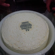 Nicola's Marketplace - DOP Aurora Manchego Kosher Cheese Wedge: 6 ounces, shown freshly-pressed in its mold with España Denominación de Origen Manchego label visible.