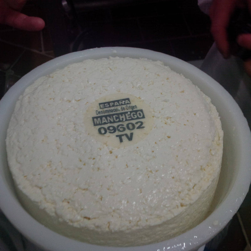 Nicola's Marketplace - DOP Aurora Manchego Kosher Cheese Wedge: 6 ounces, shown freshly-pressed in its mold with España Denominación de Origen Manchego label visible.