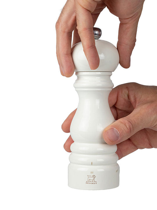 Hands hold the Peugeot | Paris u'Select Ivory Lacquered Salt Mill, showcasing its elegant design and adjustable grind settings for precise seasoning.
