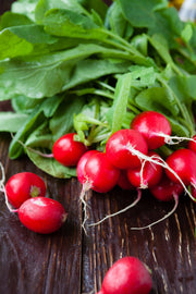 Bentley Seed Co. - Radish-Cherry Belle 1884: Fresh, round red radishes with leafy tops, ideal for salads or snacks, displayed on a wooden surface.