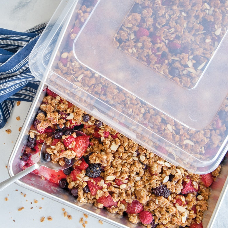 Nordic Ware Naturals High Sided Sheetcake Pan with Lid, ideal for storing and transporting baked goods, featured alongside granola with berries in a bowl.