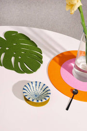 Graf Lantz - Merino Wool Felt Medium Monstera Leaf Trivet: Loden Green on table, alongside a vase and a glass, highlighting kitchen elegance.