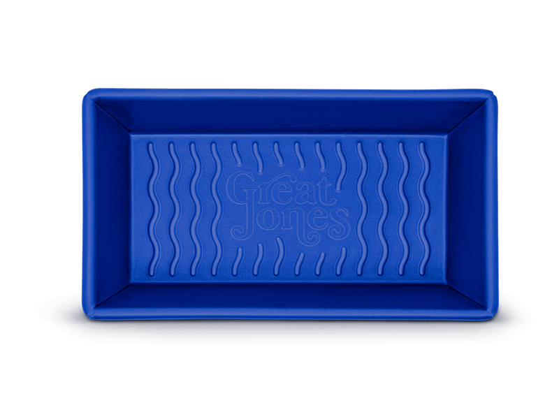 Great Jones | Breadwinner - Raspberry: A blue rectangular loaf pan with a wavy, corrugated nonstick bottom, perfect for effortless baking and easy release.
