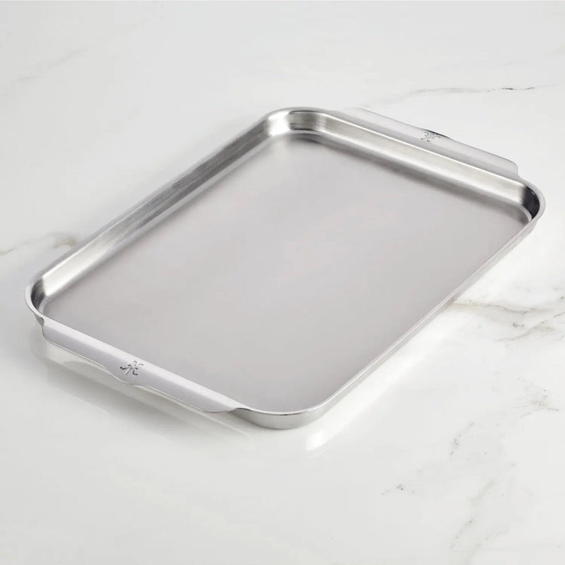 Hestan | OvenBond Tri-Ply Bakeware, Single Half Sheet Pan with rolled edges and built-in handles, showcased on a marble-style countertop, ideal for even heat distribution and durability.