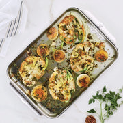 Hestan OvenBond Tri-Ply Half Sheet Pan showcasing roasted cauliflower steaks with onions, garnished with herbs and spices, highlighting its even heat distribution and durability.
