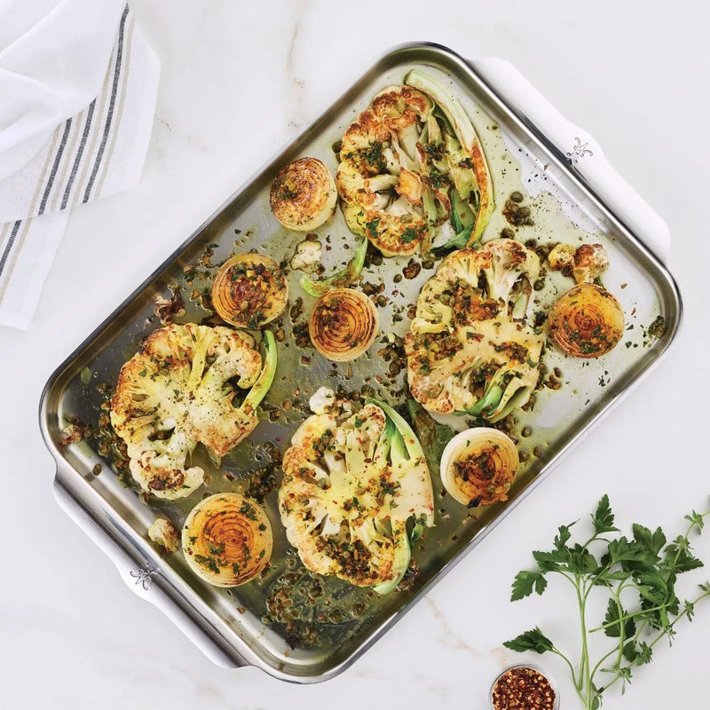 Hestan OvenBond Tri-Ply Half Sheet Pan showcasing roasted cauliflower steaks with onions, garnished with herbs and spices, highlighting its even heat distribution and durability.