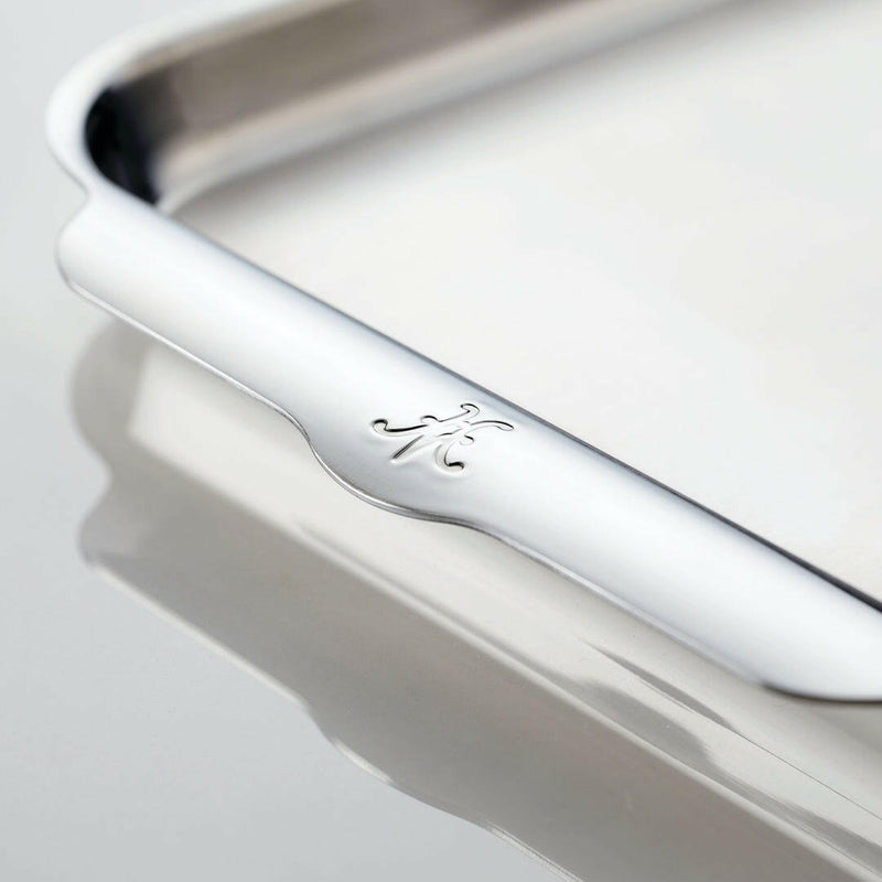 Close-up of the Hestan Provisions OvenBond Bakeware, highlighting its polished, stainless-steel surface with an embossed 龙 character on the beveled rim.