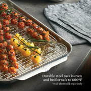 Hestan Provisions OvenBond rack on half-sheet pan with tomatoes and rosemary; durable, oven-safe to 600°F. Grey kitchen towel aside. Half sheet sold separately.