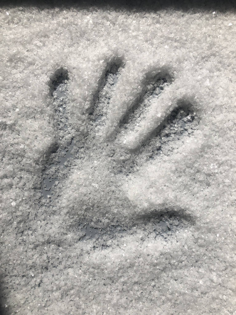 Havsnø Fine Kosher Norwegian Sea Salt on gray tray, featuring a pressed handprint in coarse crystals, perfect for versatile kitchen use.