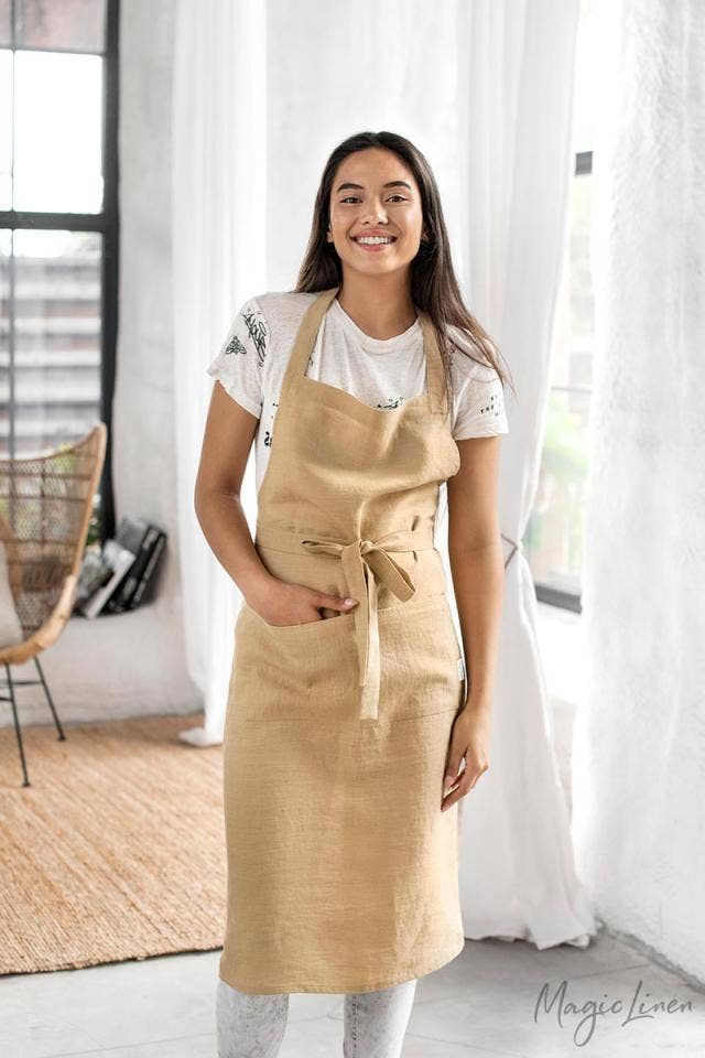 Woman wearing MagicLinen's Charcoal Grey Linen Bib Apron with Pockets, ideal for cooking or gardening, showcasing its stylish and functional design.
