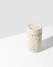 Reusable Ceramic Mug: Terrazzo Charcoal, 16 oz, with splash-resistant lid and soft-touch silicone sleeve for easy grip. Perfect for sustainable home-brewed beverages.