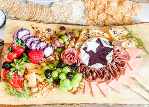 Charcuterie board featuring Southern Roots Sisters - Blackberry Pepper Jam on Brie, surrounded by meats, cheeses, sweet peppers, olives, nuts, and fresh fruits.