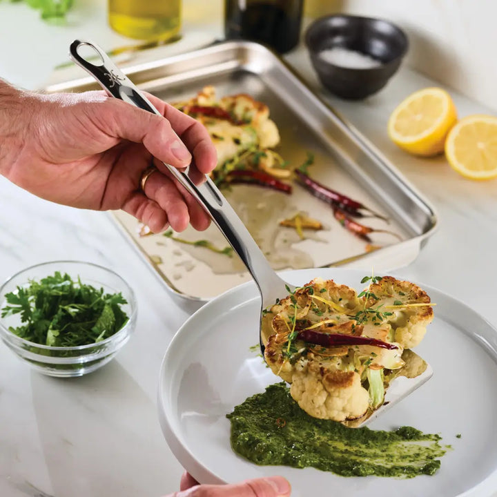 Hestan Stainless Steel Spatula/Turner being used to serve a dish, highlighting its practical design for efficient meal preparation.