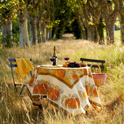 Caravan Home - Pumpkin Orange & Mustard Tablecloths: 71 x 71 decorates a picnic table with wine, grapes, and bread along a tree-lined path.