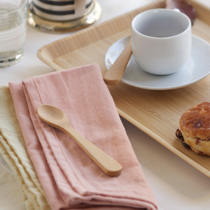 Bambu® - Bamboo Tea Spoon on a rustic bamboo tray with a ceramic cup and saucer, complemented by a raisin scone and linen napkins.