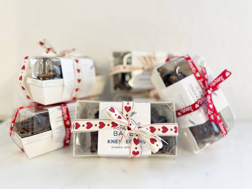 Norwegian Baked - KnekkeGodis Valentine's Special, featuring small, ribbon-tied boxes with caramel, chocolate, cranberries, and sea salt-topped crispbread treats. Perfect for gifting.