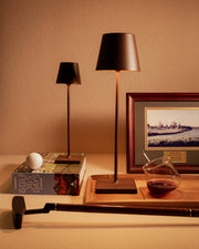 Zafferano America - Poldina Pro Cordless Lamp: Rust, featured with golf items, wine glass, and elegant accent lighting, highlighting its versatility and modern design.