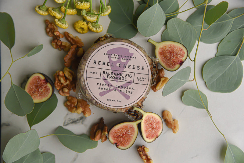 Rebel Cheese - Balsamic Fig & Walnut Fromage Plant Based - 7 oz: Round cheese with figs and nuts on marble, showcasing creamy texture and artisanal ingredients.