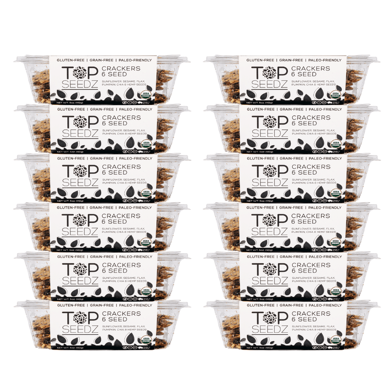 Top Seedz 6 Seed Crackers in labeled plastic containers, showcasing grain-free, vegan, organic ingredients. Sold in 5oz boxes with 12 per case.