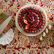 Couleur Nature - Noel Red & Green French Tablecloth under a berry tart, showcasing festive elegance with handprinted holiday designs on finely crafted linen.