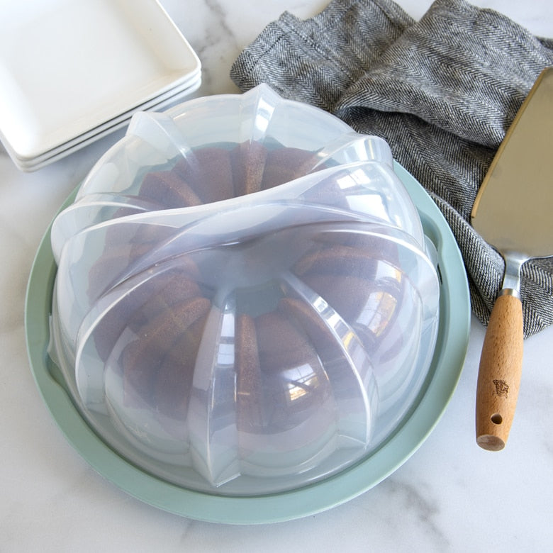 Nordic Ware | Translucent Bundt® Cake Keeper with twist-to-lock lid, ideal for storing and transporting Bundt® cakes, featured in a plastic container.