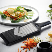 GEFU | Violi 2.0 Adjustable Mandoline beside a plate of sliced vegetables, highlighting its functionality for precise vegetable preparation.
