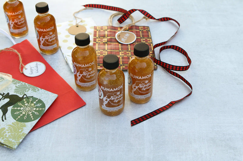 Runamok Mini Sparkle Syrup 60ml bottles arranged with festive gift-wrapping items, highlighting their appeal as holiday gifts or unique kitchen store offerings.