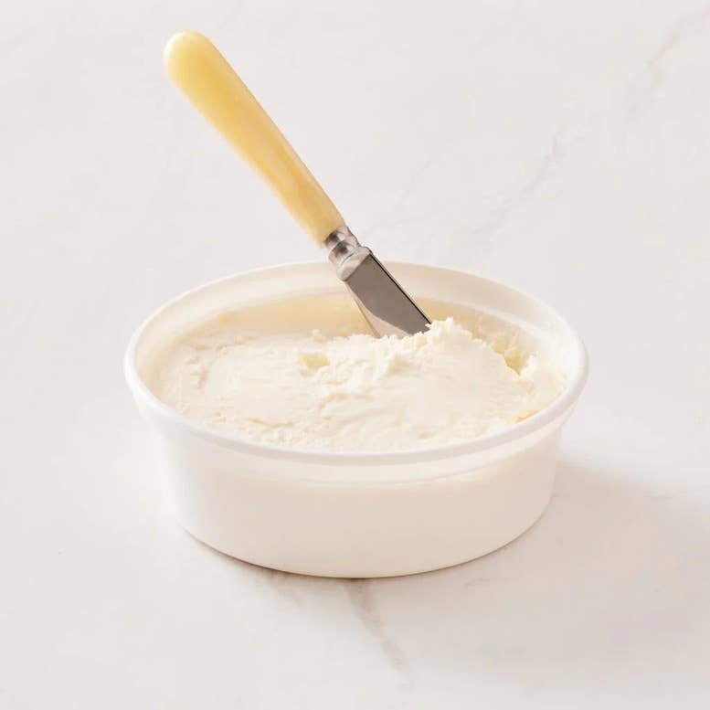Perrystead Dairy - The Real Philly Schmear in a bowl with a butter knife, showcasing its creamy, spreadable texture, ideal for kitchen enthusiasts and culinary creations.