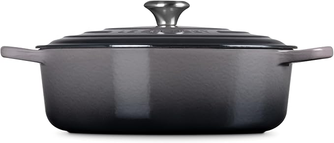 Le Creuset Signature Round Wide Oven in enameled cast iron, featuring side handles and a fitted lid with a metal knob, ideal for versatile cooking.