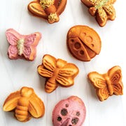 Nordic Ware | Backyard Bugs Pan, showcasing eight insect-shaped cookies including butterflies, bees, and ladybugs, highlighting the pan's detailed baking capabilities.