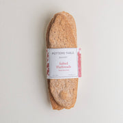 Potters Table - Salted Olive Oil Flatbreads wrapped in a labeled paper band, showcasing hand-stretched, organic whole grain crackers for pairing with cheese or spreads.