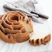 Nordic Ware | Rose Bundt® Pan with a cake showcasing intricate rose-shaped detailing, a slice cut out, and a knife alongside, highlighting its premium nonstick finish.