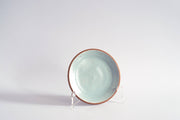 RachaelPots - Dessert Plate: Sage, a hand-thrown ceramic plate with speckled aqua glaze and reddish clay rim, displayed upright, perfect for desserts.