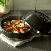 Emile Henry | Bread Pot, Charcoal with lid slightly open, revealing steaming braised vegetables, showcasing its versatile use beyond baking bread.