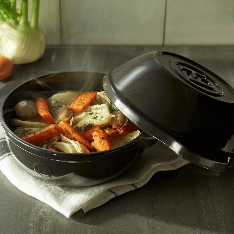 Emile Henry | Bread Pot, Charcoal with lid slightly open, revealing steaming braised vegetables, showcasing its versatile use beyond baking bread.