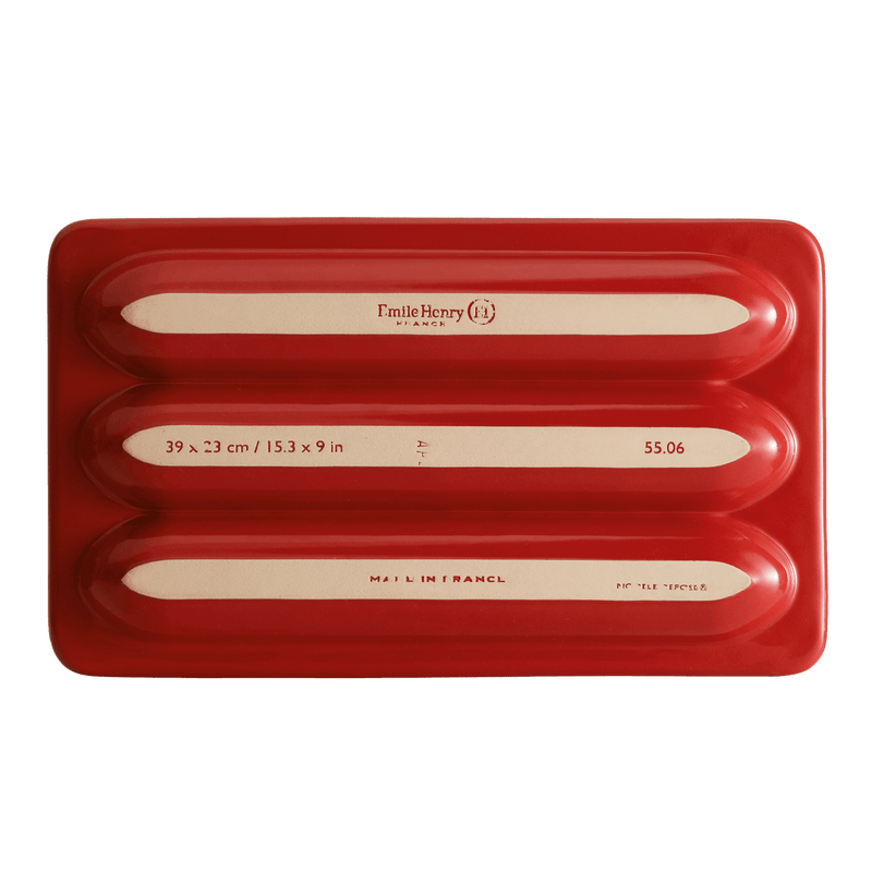 Emile Henry | Baguette Baker, Burgundy: A ceramic baker with three molds for baguettes. Features ribs for non-stick baking and a lid for ideal humidity. Made in France.