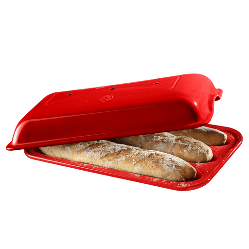 Emile Henry | Baguette Baker, Burgundy: Bright-red silicone mold with a snap-on lid, showcasing two freshly baked baguettes, designed for perfect crusts and easy cleaning.