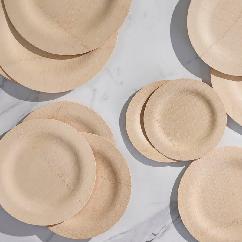 Top-down view of bambu® Disposable Bamboo Round Plates, 11 inches, overlapping on marble; eco-friendly, compostable, attractive option for events and gatherings.
