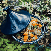 Emile Henry | Tagine, Ocean: Deep blue ceramic tagine with a conical lid, revealing a fragrant stew with squash, chickpeas, and meat, perfect for tender, flavorful cooking.
