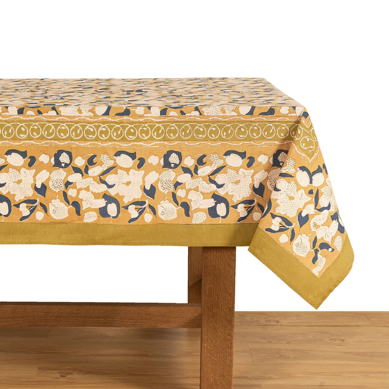 Couleur Nature - Forest Harvest Mustard & Blue tablecloth featuring floral motifs on a wooden table, showcasing artisan craftsmanship and rich Provençal-inspired design.