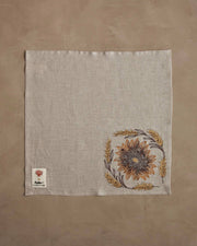 Coral & Tusk - Sunflower and Wheat Dinner Napkin, showcasing an embroidered sunflower with wheat wreath on natural linen, perfect for autumnal table settings.