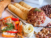 Cheeseboard featuring Southern Roots Sisters - Raspberry Chipotle Jam with a bacon cheese ball, crackers, filled peppers, nuts, and butter rose, perfect for entertaining.