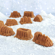 Nordic Ware Train Cake Pan featuring nine distinct train-shaped molds, perfect for creative baking with children, displayed in a snowy outdoor setting.