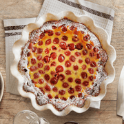 Emile Henry | Deep Ruffled Pie Dish, Clay, showcasing a baked cherry clafoutis, illustrating the dish's rustic elegance and functional scalloped edges.